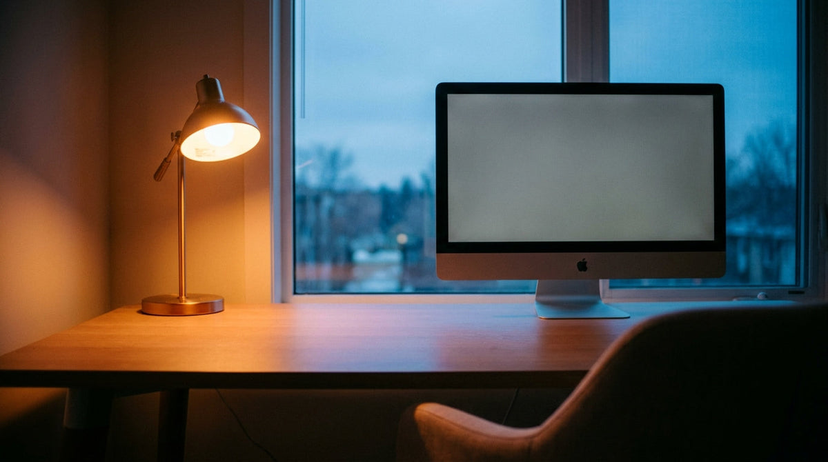 Home office monitor showing a neutral gray swatch under mixed warm lamp and cool daylight, illustrating how room lighting affects color perception
