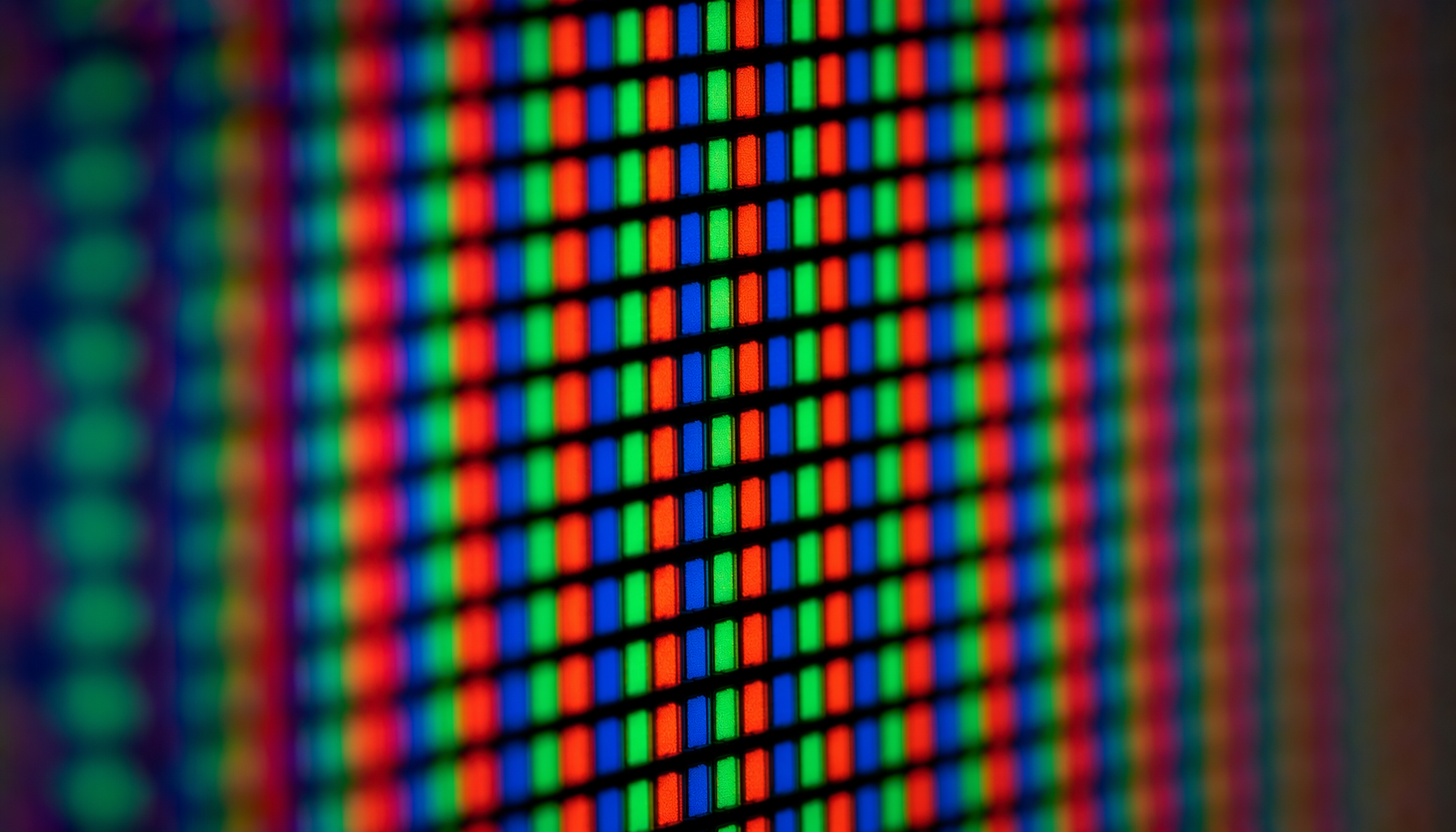 Macro view of an LCD panel surface showing the RGB subpixel grid with red, green, and blue cells separated by a black matrix